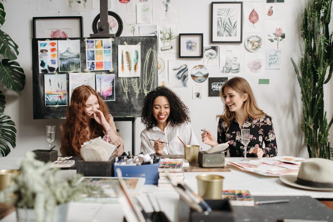 Women sitting around a table painting and laughing