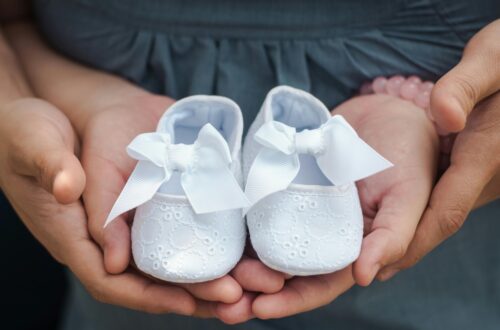 Parents holding white baby booties