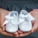 Parents holding white baby booties